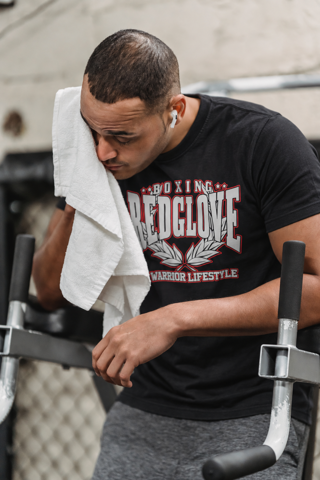 Mockup de camiseta negra RG Warrior Lifestyle en un atleta descansando en el gimnasio con toalla